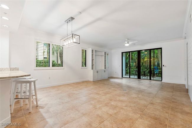 Living room showcasing tile floors, built in cabinetry, plenty of windows and natural light | Image 9