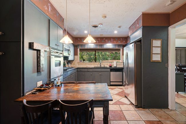 Kitchen featuring stainless steel appliances, dark countertops, tasteful backsplash, gray cabinets, and light tile patterned floors | Image 7