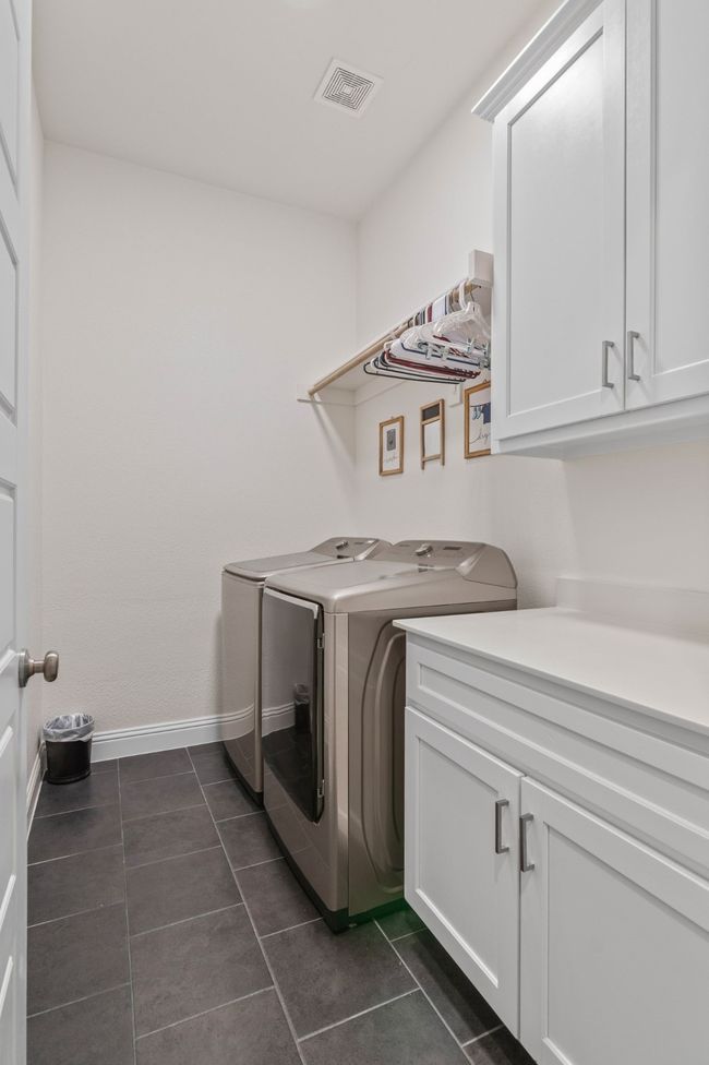 Laundry room featuring cabinet space, visible vents, washer and dryer, and dark tile patterned flooring | Image 22