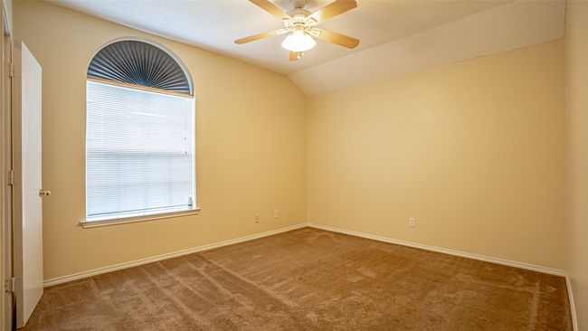 Carpeted spare room featuring ceiling fan, baseboards, and lofted ceiling | Image 10