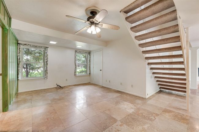 Unfurnished room with baseboards, ceiling fan, and stairway | Image 10