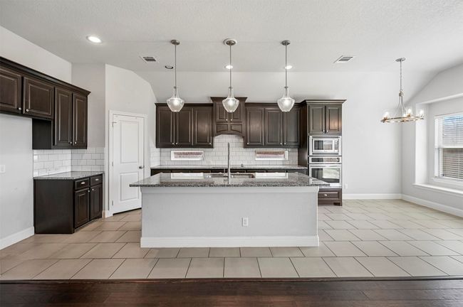 Kitchen featuring stainless steel appliances, lofted ceiling, and visible vents | Image 17