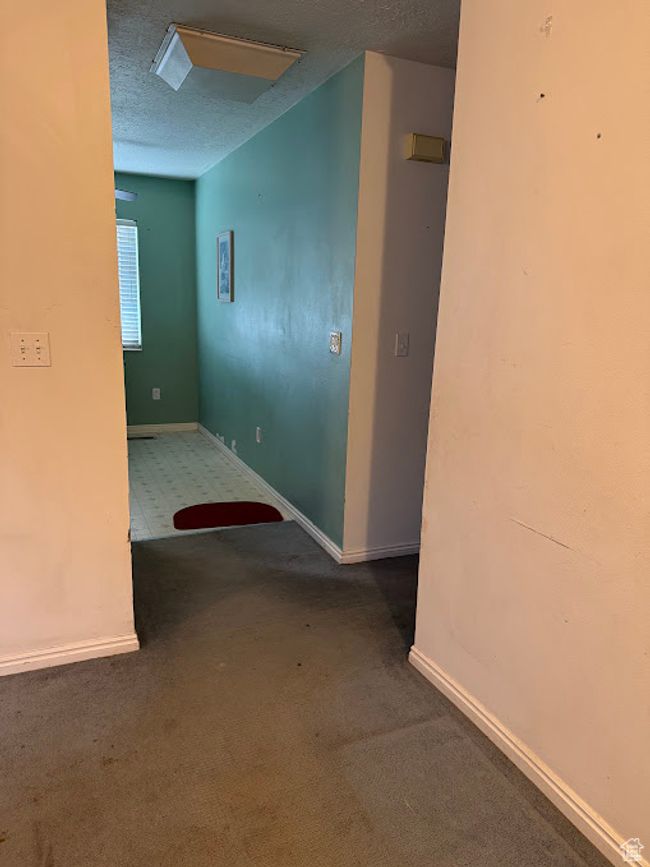 Hallway featuring carpet, a textured ceiling, and baseboards | Image 17