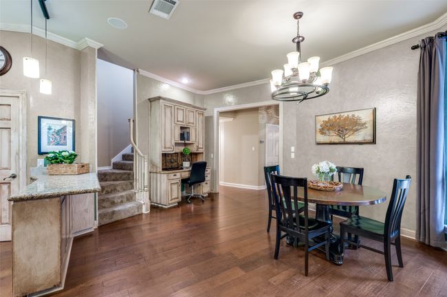 Dining room featuring dark wood-type flooring, a chandelier, stairway, ornamental molding, and baseboards | Image 10