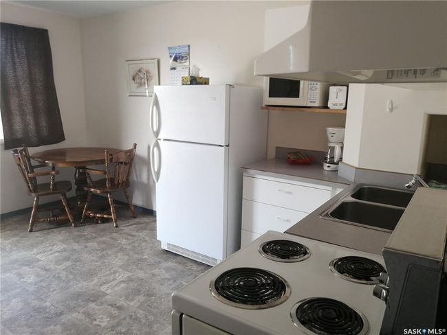 Kitchen featuring white appliances, exhaust hood, white cabinets, and stone finish flooring | Image 33