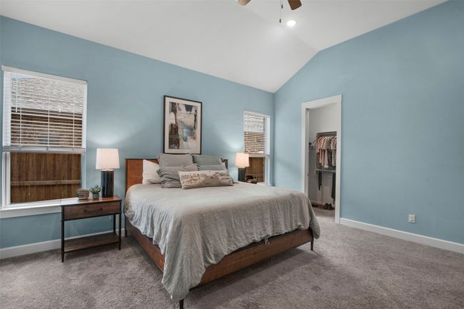 Carpeted bedroom with lofted ceiling, baseboards, a walk in closet, a ceiling fan, and a closet | Image 13