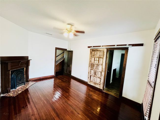 primary bedroom with wood flooring, ceiling fan, and a decorative fireplace, barndoor to ensuite bathroom | Image 5