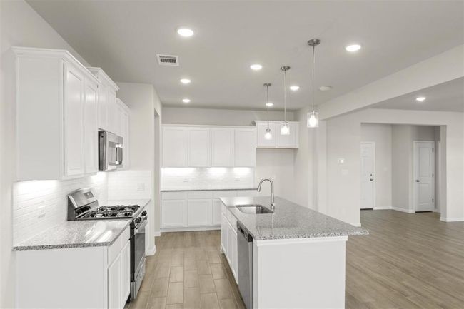 Kitchen featuring stainless steel appliances, visible vents, a sink, and light wood-style flooring | Image 11