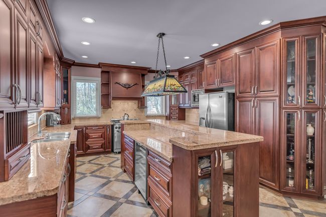 Kitchen featuring appliances with stainless steel finishes, inlaid floor details, recessed lighting, beverage cooler, and a sink | Image 12