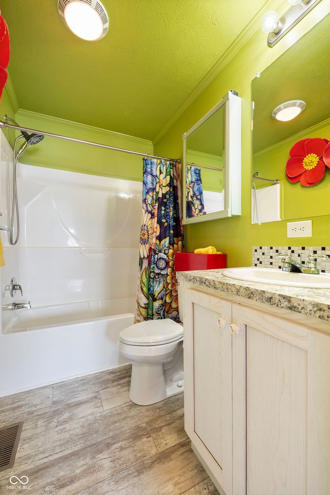 full bath featuring ornamental molding, shower / bathtub combination with curtain, vanity, toilet, and wood finished floors | Image 23