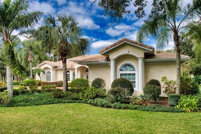 Nestled amid a lush landscape, this home showcases an exceptional blend of classical design and modern landscaping. The striking arched detailing above the windows adds architectural interest, complemented by a rich palette of garden greenery that frames the property beautifully. Majestic palm trees rise against a vibrant sky, enhancing the tropical allure of the home. This property offers a serene retreat, seamlessly combining the comfort of indoor elegance with the splendor of outdoor living. | Image 3