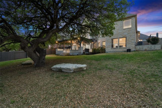 Rear view of property with stone siding, a yard, central AC, and fence | Image 37