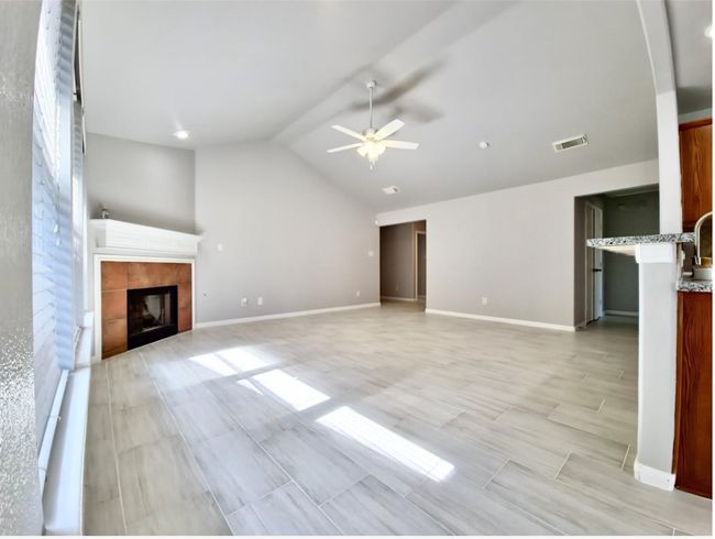 Unfurnished living room featuring lofted ceiling, ceiling fan, and a fireplace | Image 7