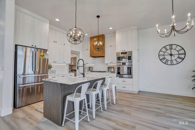 Kitchen with appliances with stainless steel finishes, a chandelier, tasteful backsplash, a kitchen breakfast bar, and a center island with sink | Image 8