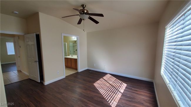 Unfurnished bedroom featuring connected bathroom, baseboards, vaulted ceiling, and wood finished floors | Image 10