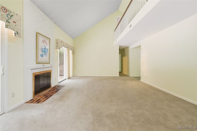 Unfurnished living room featuring carpet, high vaulted ceiling, and a fireplace with flush hearth | Image 11