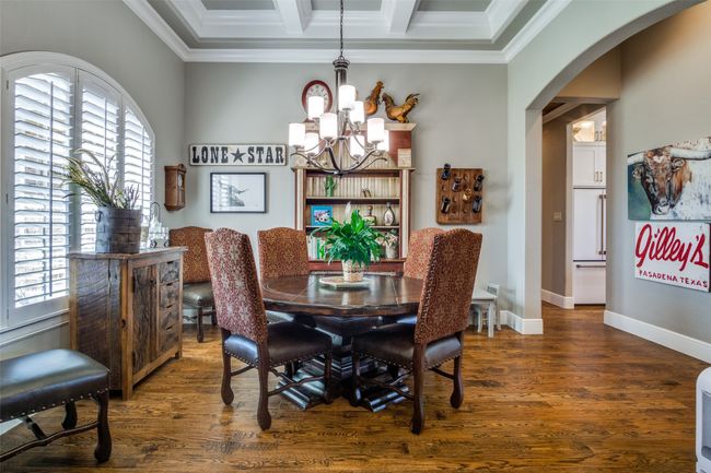 Dining area featuring arched walkways, crown molding, a notable chandelier, and wood finished floors | Image 6
