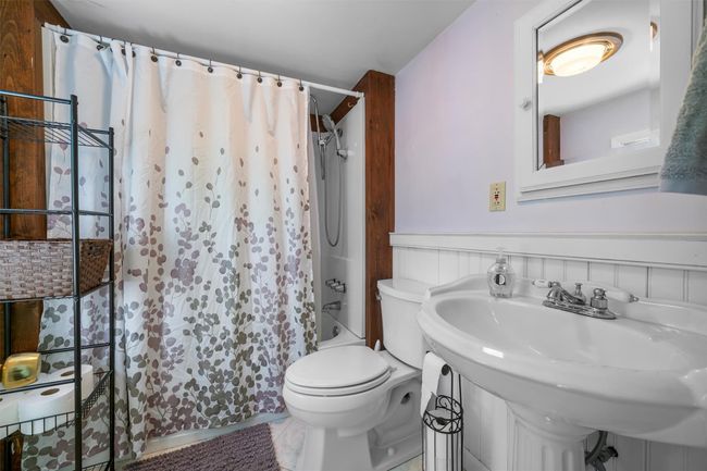 Full bath featuring toilet, shower / bath combo with shower curtain, and a sink | Image 12