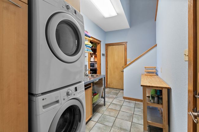 Clothes washing area featuring stacked washer and dryer and light tile patterned floors | Image 22