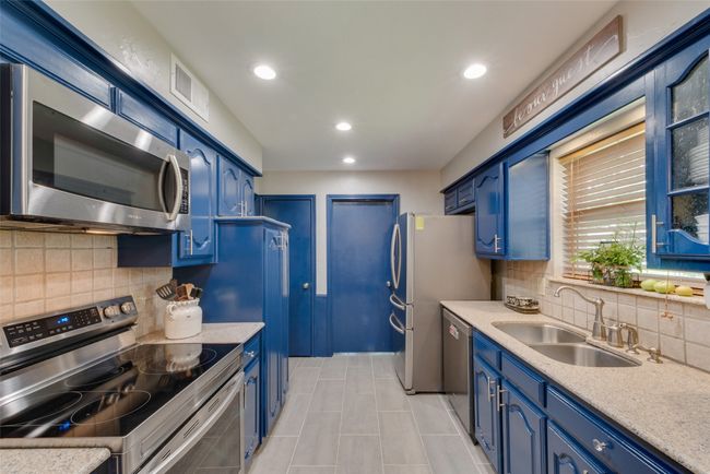 Kitchen with appliances with stainless steel finishes, blue cabinetry, a sink, backsplash, and light countertops | Image 16