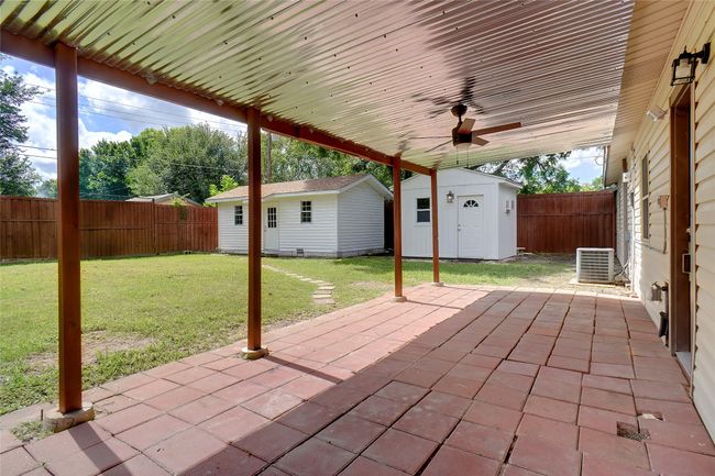 8 ft board on board fenced backyard featuring a patio area, a ceiling fan, and two outside building | Image 18