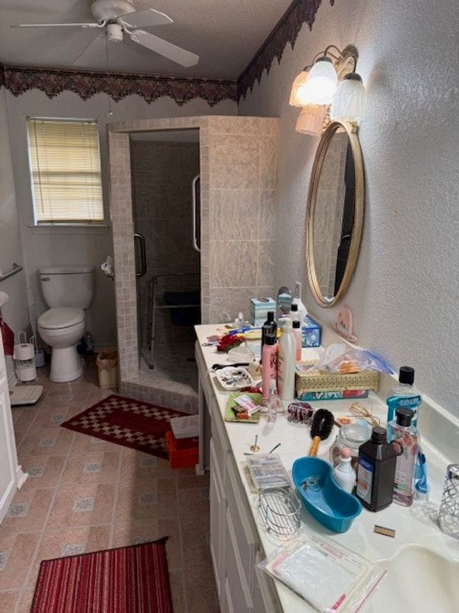 Bathroom with a ceiling fan, a shower stall, vanity, and toilet | Image 27