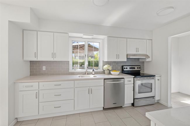 Kitchen with a sink, stainless steel appliances, backsplash, under cabinet range hood, and light countertops | Image 10