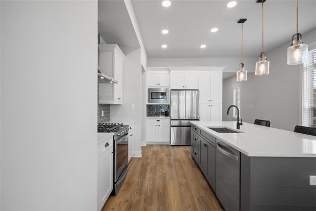 Kitchen offers eat-at island, stainless steel appliances, upgraded lighting, recessed lighting, LVP flooring. Open concept to dining area and great room | Image 7