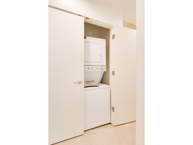 Laundry room featuring stacked washer / dryer and light colored carpet | Image 18