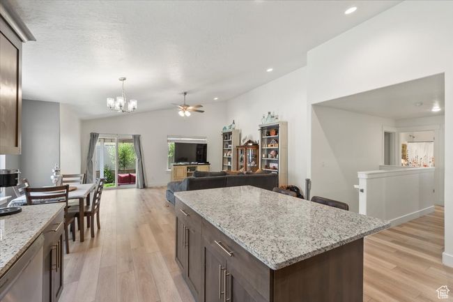 Kitchen featuring vaulted ceiling, a chandelier, light wood-style flooring, ceiling fan, and dark brown cabinetry | Image 10