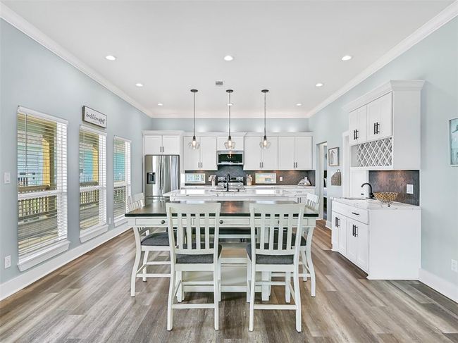 The expansive kitchen and dining area with designer lighting, quartz countertops, and a built-in wet bar are perfectly designed for gathering, entertaining, and enjoying beach life in style. | Image 13