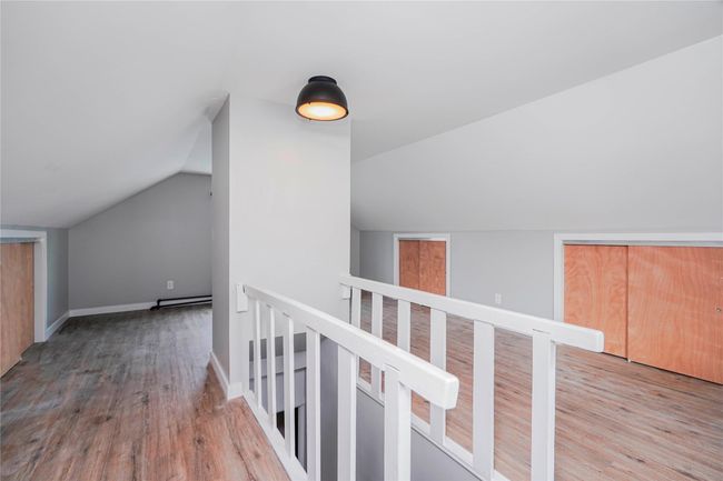 Hall featuring baseboards, an upstairs landing, baseboard heating, vaulted ceiling, and wood finished floors | Image 26