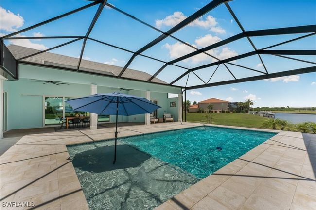 Swimming pool with a ceiling fan, a patio, a water view, and a lanai | Image 34
