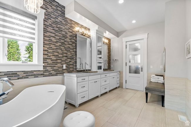 Full bath featuring a freestanding tub, a chandelier, a sink, tile walls, and double vanity | Image 37