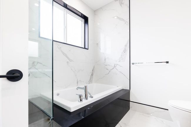 Full bathroom featuring marble finish flooring, a tub, and toilet | Image 30