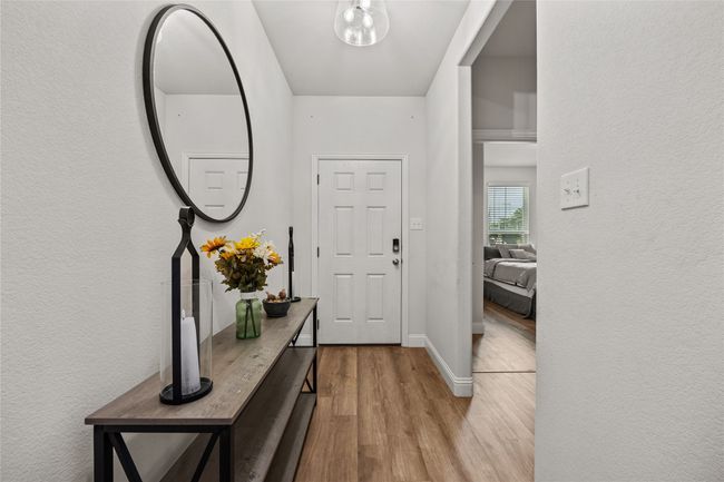 Foyer featuring wood finished floors, a textured wall, and baseboards | Image 7