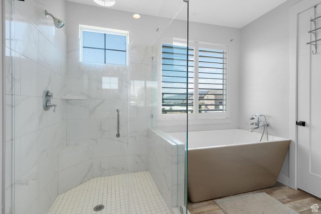 Primary suite bathroom featuring healthy amount of natural light, a stall shower, a freestanding tub, and wood finished floors | Image 14