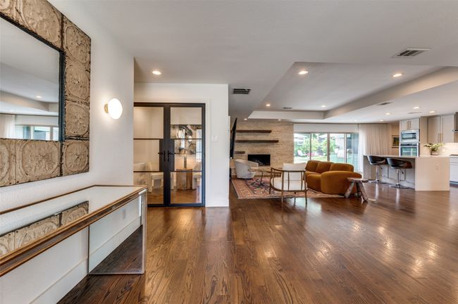 Living area with french doors, a tray ceiling, wood finished floors, a fireplace, and recessed lighting | Image 5