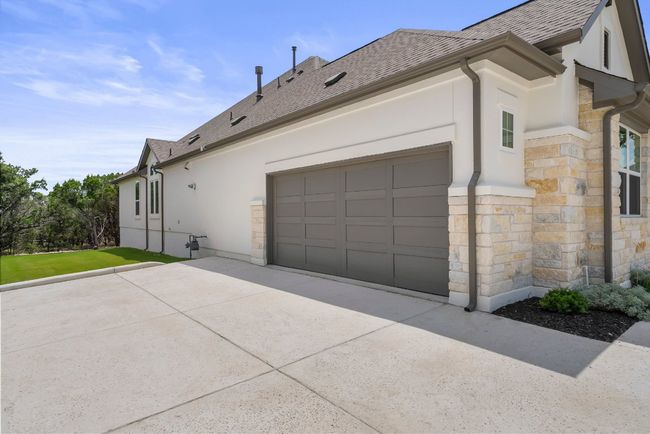 View of side of property featuring stone siding, stucco siding, concrete driveway, and a shingled roof | Image 33