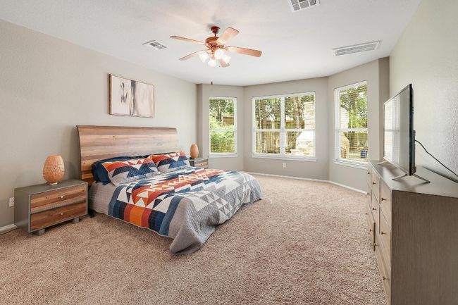 The primary bedroom feels like your own secluded getaway, with a large bay window that captures the serene views of the private backyard, letting in natural light and creating a peaceful retreat | Image 5