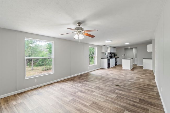 Unfurnished living room featuring light wood-type flooring, visible vents, baseboards, and ceiling fan | Image 6