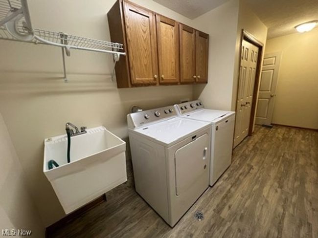 Laundry area with washing machine and dryer, dark wood-type flooring, and cabinet space | Image 27