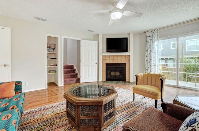 Living room featuring a textured ceiling, healthy amount of natural light, wood finished floors, a tiled fireplace, and a ceiling fan | Image 11