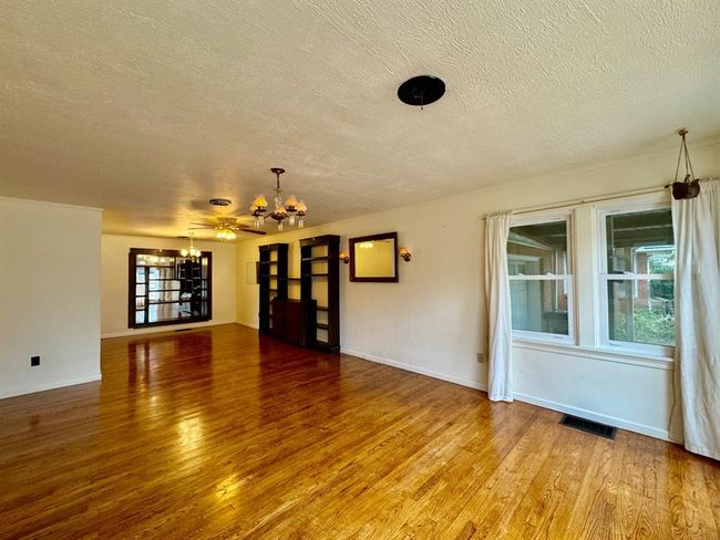 Unfurnished living room with a chandelier, a textured ceiling, and light wood-style flooring | Image 4