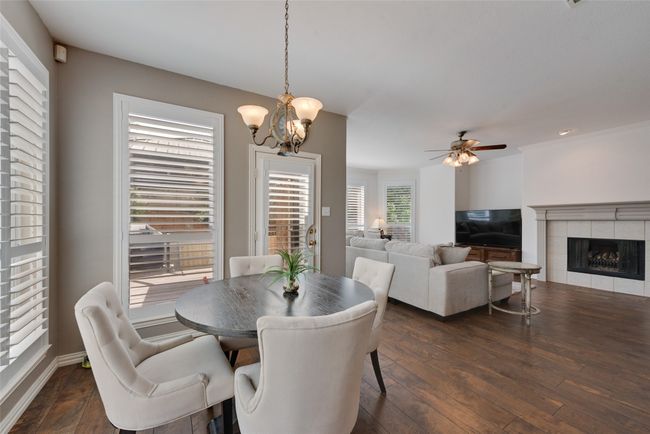 Dining area featuring a tile fireplace, ceiling fan with notable chandelier, baseboards, and wood finished floors | Image 9