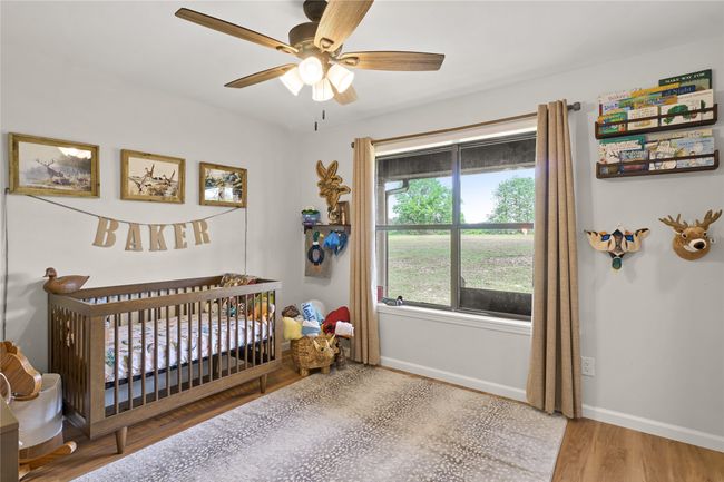 Bedroom with a crib, wood finished floors, and ceiling fan | Image 23