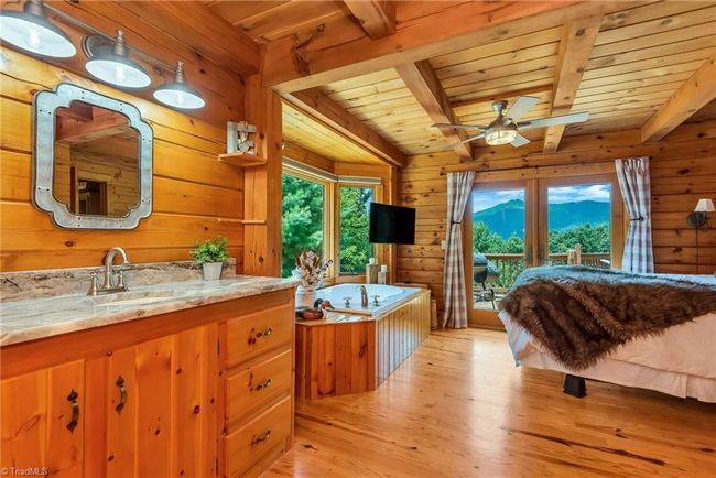 The upper level of the log cabin boasts a cozy loft area leading to two bedrooms, along with one full bath and one half bath, offering a charming and functional layout perfect for family living or guest accommodations. | Image 29