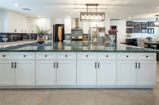 Kitchen with visible vents, white cabinets, appliances with stainless steel finishes, wall chimney range hood, and tasteful backsplash | Image 12