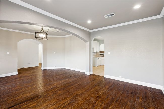 Empty room with light hardwood / wood-style floors, crown molding, and a notable chandelier | Image 23