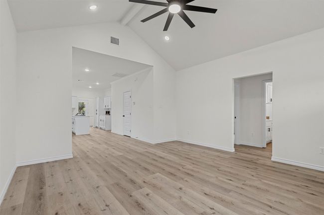 Unfurnished living room with light hardwood / wood-style floors, high vaulted ceiling, ceiling fan, and beam ceiling | Image 6